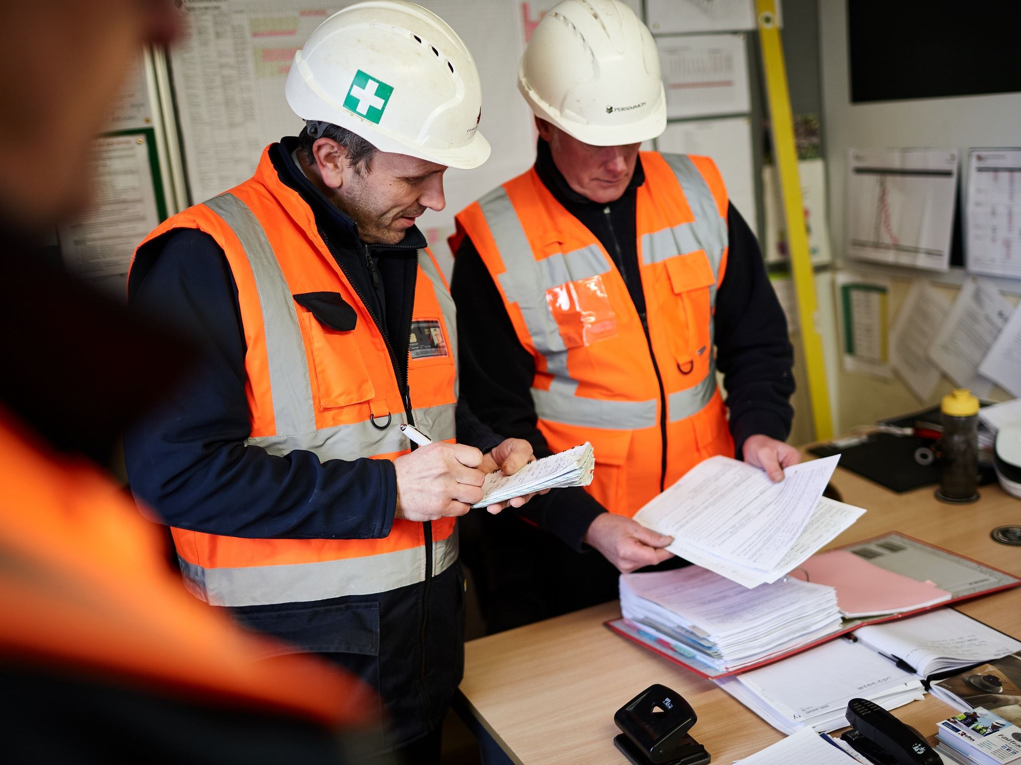 Builders looking at paperwork in hi-vis vests and hard hats