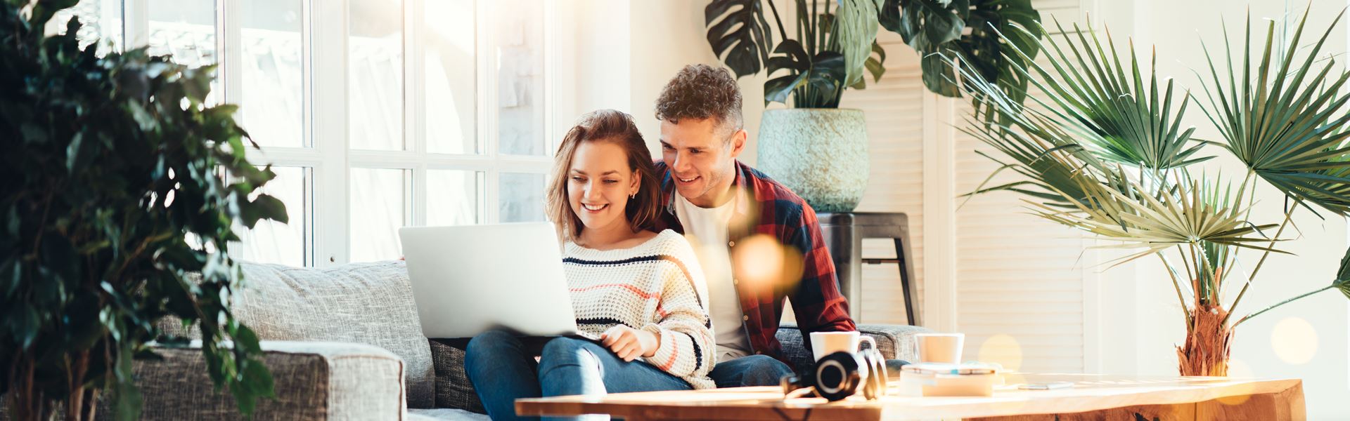 Couple on Couch with Laptop Surrounded by Plants