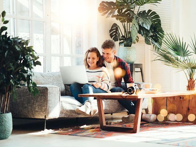Couple on Couch with Laptop Surrounded by Plants
