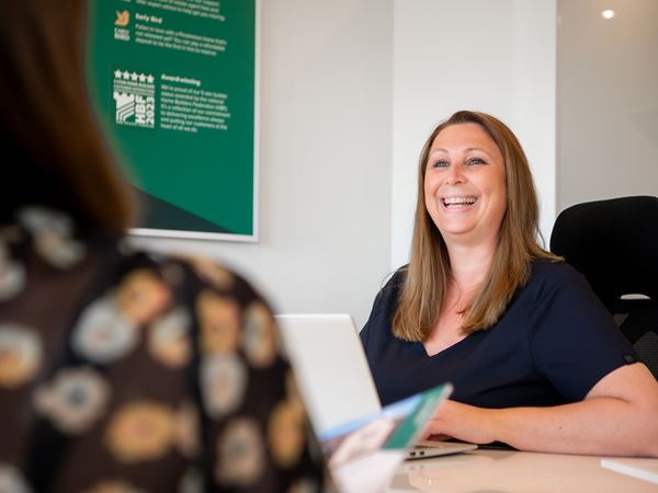 Smiling Persimmon sales advisor sitting at a desk