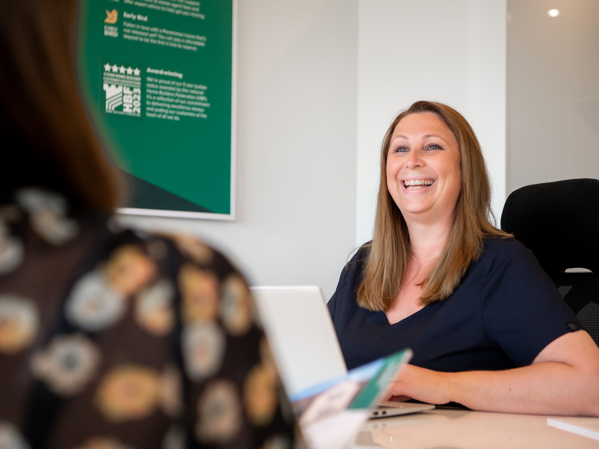 Smiling Persimmon sales advisor sitting at a desk