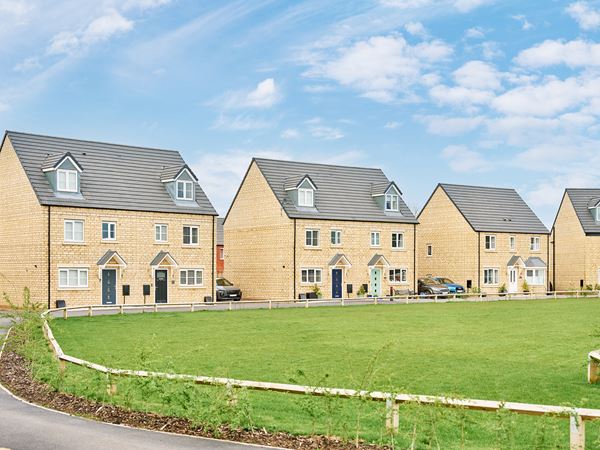 Row of pale brick new build houses on a green