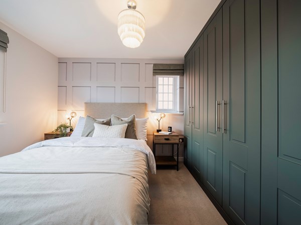 A modern bedroom in a new build Persimmon home with built in green wardrobes